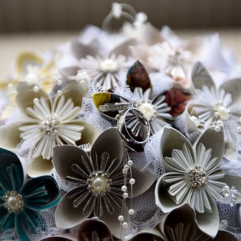 a picture of paper flowers with two wedding rings on top