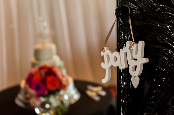 A picture of a sign stating &#039;party&#039; with a wedding cake and flowers in the background
