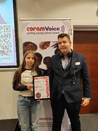 Girl and boy stood holding an award