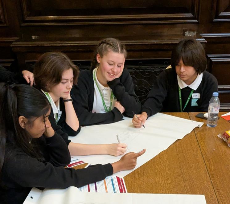 4 young people sat around a table discussing at a pop up parliament