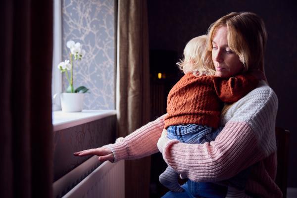 Woman holding child with her hand over a radiator
